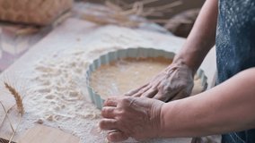 Women's hands with dough. A person prepares homemade pastries from shortcrust pastry, in her hands is a mold and flour. Hands of an adult with wrinkles. 4k footage