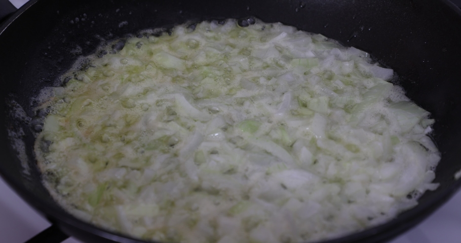 Sauteing the onion in butter in a pan on the gas stove, very low heat, cut into medium and small pieces, firm and transparent consistency. Concept of healthy food made at home. Static shot | Shutterstock HD Video #1094970083