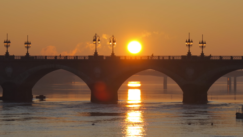 Pont de Pierre bridge in Bordeaux, France at sunrise with an orange light