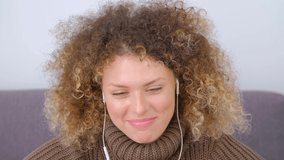 Happy white woman in headset talking on web camera. Cheerful curly female speaking on video call. Download stock video clip of cute girl with curls who speaks with friends online