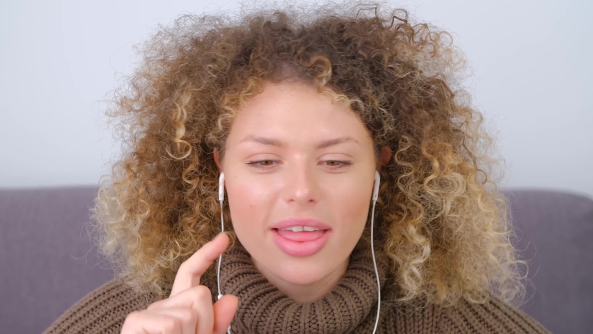 Happy white woman in headset talking on web camera. Cheerful curly female speaking on video call | Shutterstock HD Video #1094974177