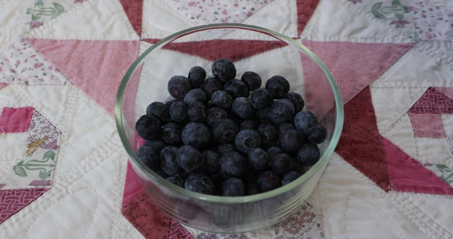 Group of blueberries falling into a round glass bowl, cloth tablecloth, delicious, dark blue in color and organically grown in the garden. Concept of bio, biological and natural cultivation at home | Shutterstock HD Video #1094975031