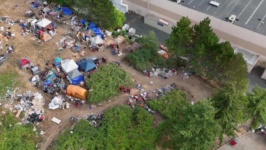 Overhead drone shot of a homeless camp in Washington State with trash spread across the ground. Royalty-Free Stock Footage #1094975479