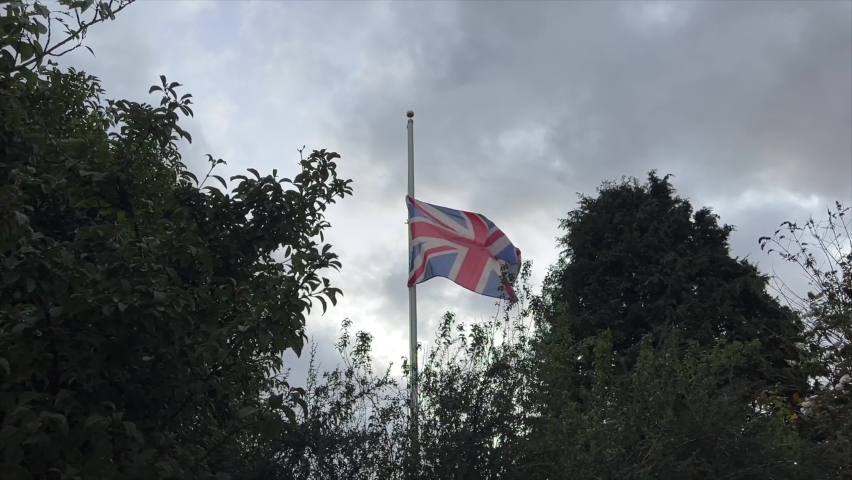 Slow motion half mast UK Union Jack Flag, between trees, fluttering in a light breeze, | Shutterstock HD Video #1094975491