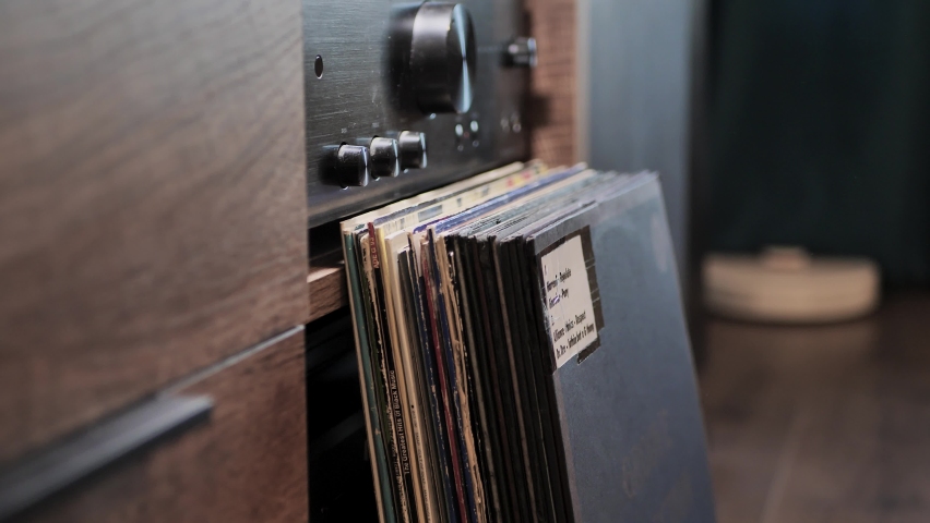 Looking through vinyl records collection at home. Searching for a DJ single or album. Selecting quality music to listen to on a turntable. The amplifier on the background. Man hands close-up. | Shutterstock HD Video #1094975735