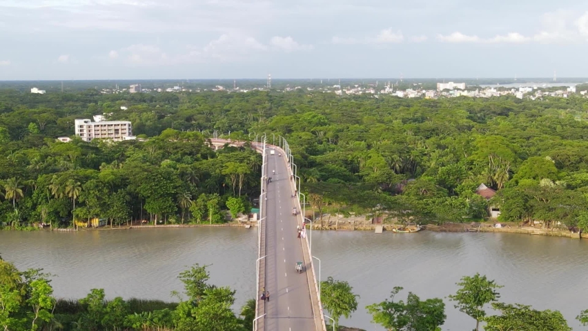 Aerial descending view of Viaduct bridge over River with Forested riverbank, vehicles driving by, Bangladesh | Shutterstock HD Video #1094976097