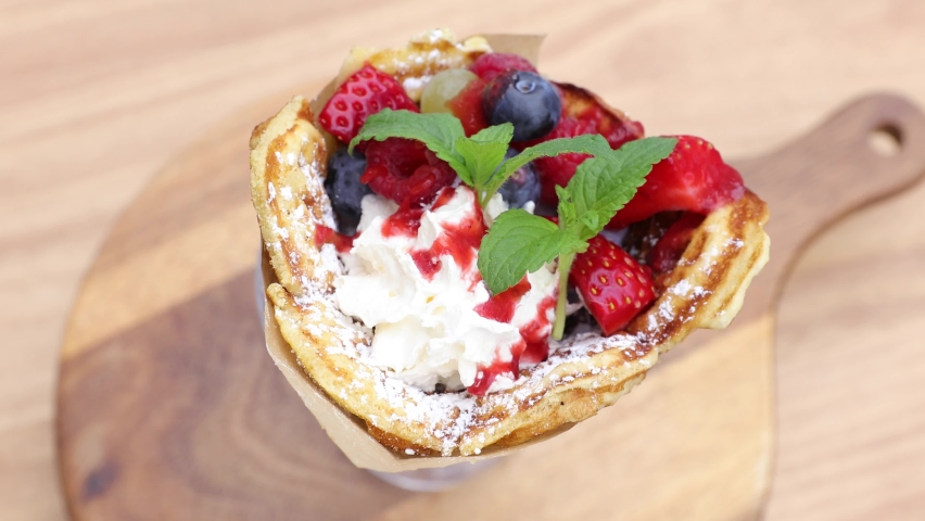Waffle in a glass cup decorated with whipped cream, strawberries, blueberries and mince. Fruits topped with powdered sugar. | Shutterstock HD Video #1094976249