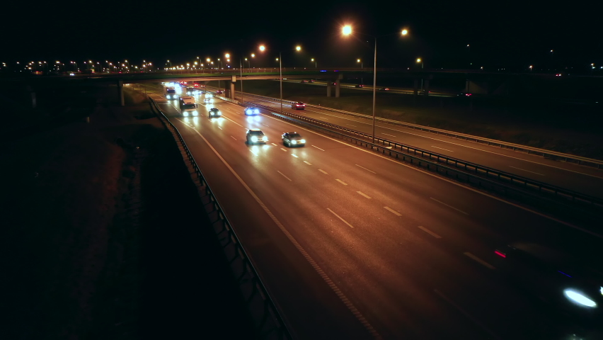 A drone shot over the head of cars driving on a multi-lane highway suburbs of Warsaw night. Poland. The drone flies to the right, panning cars, then forward, reaching the bridge and interchange  Royalty-Free Stock Footage #1094976941