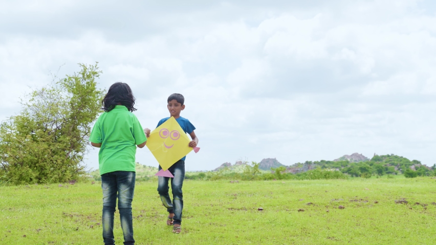 Excited teenager kids flying kite by enjoying on top of mountain - concept of hapiness, weekend and holidays activities.