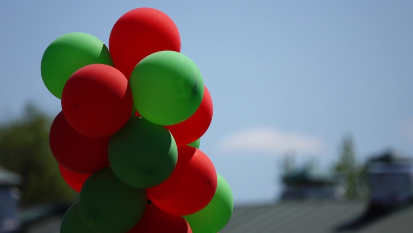 Lot of red and green balloons against background of blue sky in summer city park. | Shutterstock HD Video #1094981339