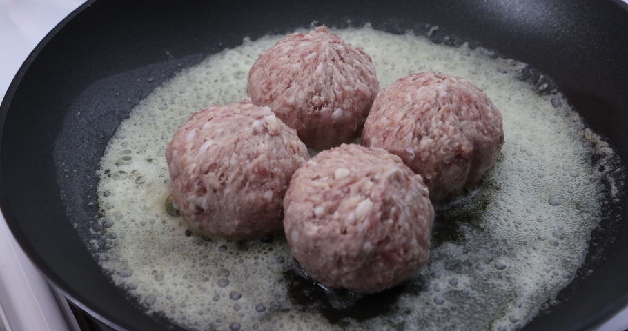 Placing four raw meatballs in melted butter to fry them, pork meat, frying pan on a gas stove, homemade delicious food. Concept of healthy food in traditional kitchen | Shutterstock HD Video #1094982001