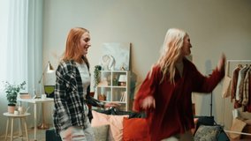 Girlfriends dancing together at home in living room. Young women recording dance video for musical clip. Bloggers making music content for channel.