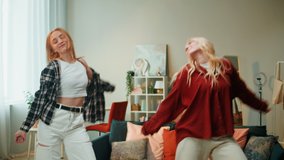 Girlfriends dancing together at home in living room. Young women recording dance video for musical clip. Bloggers making music content for channel.