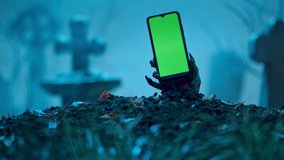 Zombie hand rising up smartphone with green screen out of grave. Holiday event halloween concept. - Powered by Shutterstock - Get 15% off with code: PIKWIZARD15