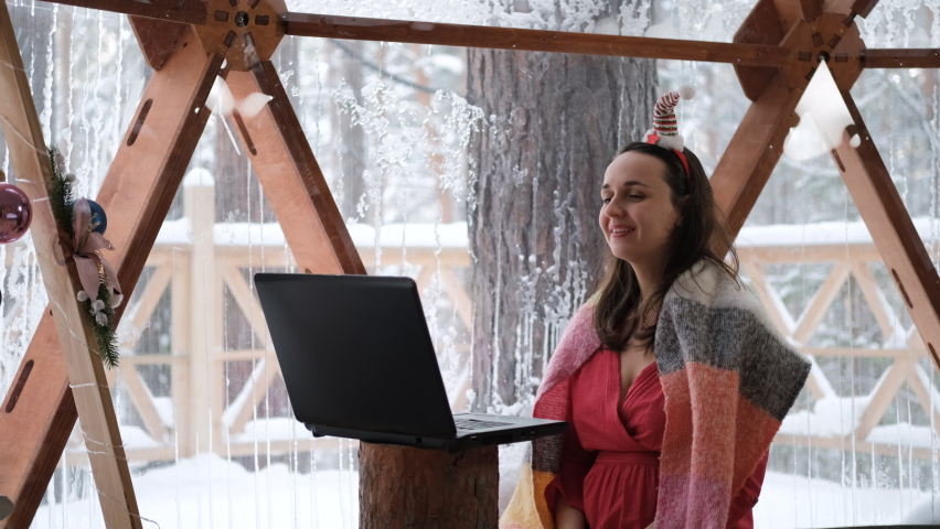 Happy woman having videocall from glamping on Christmas day, showing view from dome camping to her viewers. Congratulating family or friends by using laptop, slow motion. Glamping vacation concept | Shutterstock HD Video #1094984771