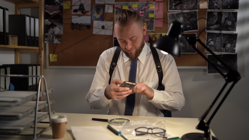 Detective working in the office with evidence, using a mobile phone taking a photo of the evidence for criminal case | Shutterstock HD Video #1094985259
