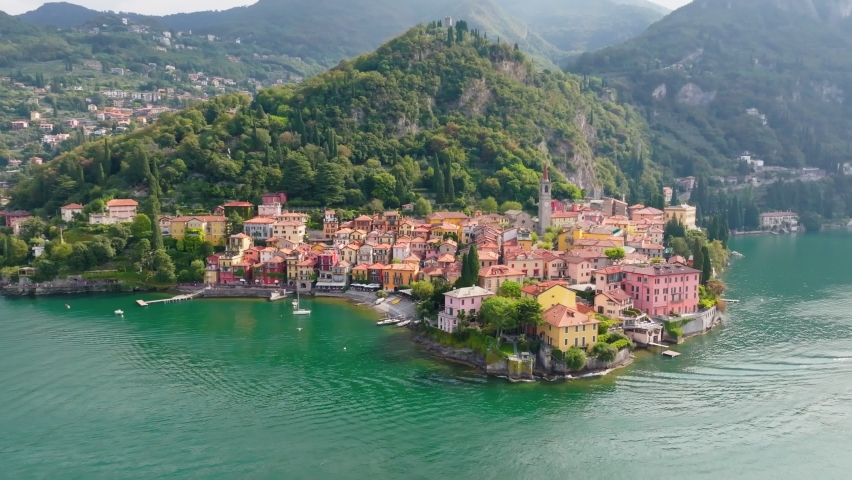 Flying over colorful houses of Varenna village on Lake Como, Italy. Summer luxury tourism landmark romantic honeymoon travel destination. Aerial shot ol old town Varenna on the coast of Lake Como