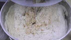 Cake dough making. Machine knead bread dough. Raw dough in a industrial bakery dough mixer, food concept. Stock footage. 4K resolution video.