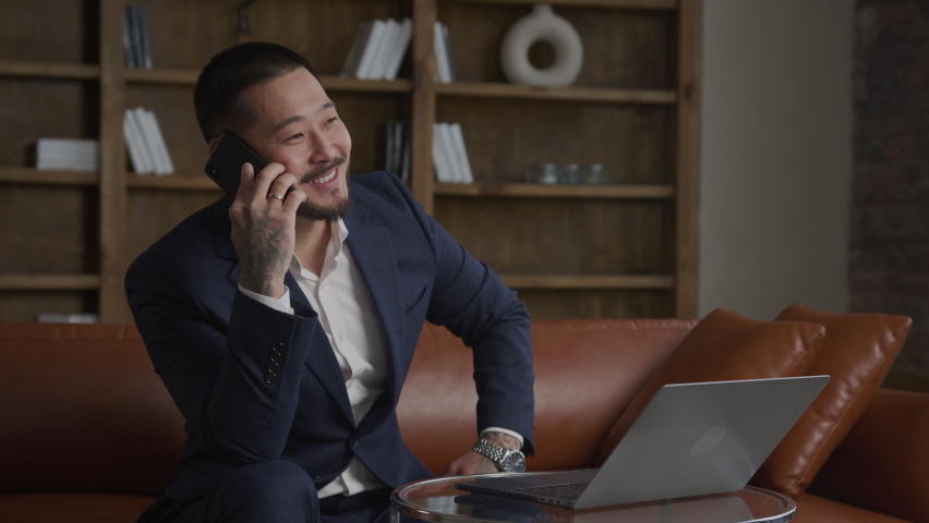 Happy Asian businessman getting a job offer on a call on smart phone in his loft office | Shutterstock HD Video #1094988013