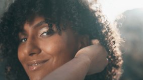 Closeup pretty woman face with curly black hair smiling on camera. Portrait of young african american girl posing on nature touching hairstyle. Beautiful happy lady standing alone on sunny nature. - Powered by Shutterstock - Get 15% off with code: PIKWIZARD15