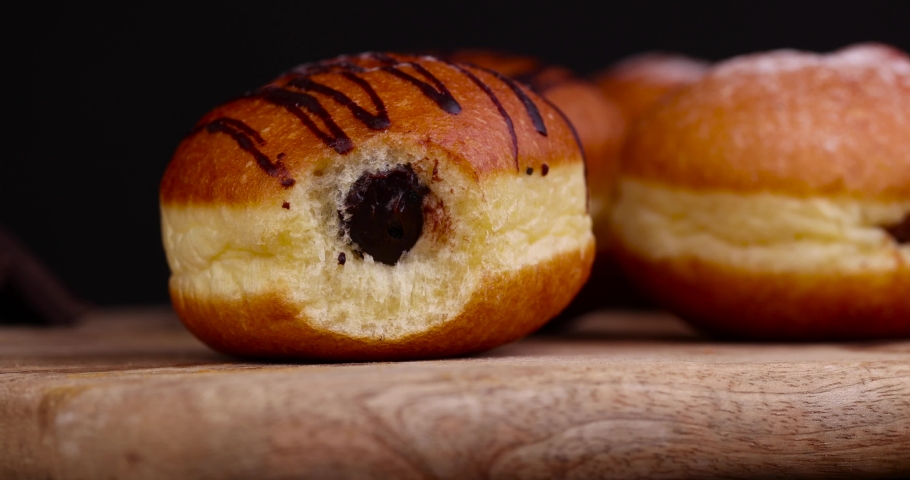 Cut into half a high-calorie doughnut with a sweet filling, dividing into half a fat Berlin doughnut | Shutterstock HD Video #1094990965