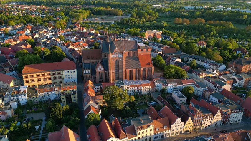 Huge red brick church with large windows.
Wonderful aerial view flight panorama overview drone
in Wismar germany at summer day golden hour August 2022. Marnitz 4k Cinematic from above | Shutterstock HD Video #1094992089