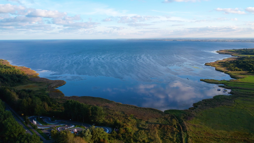 Aerial view overlooking blue Baltic sea surrounding green forest island landscape, Poland