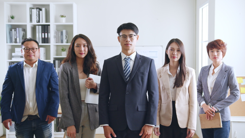 Portrait of smiling group Asian professional confident business people team standing and looking at camera | Shutterstock HD Video #1094992673