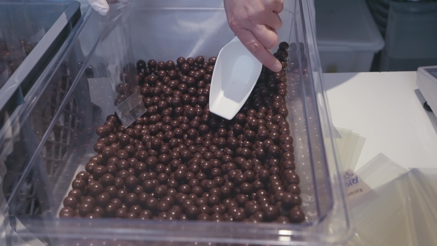 Woman packaging chocolate brown balls in clean package in production plant, slow motion | Shutterstock HD Video #1094992809