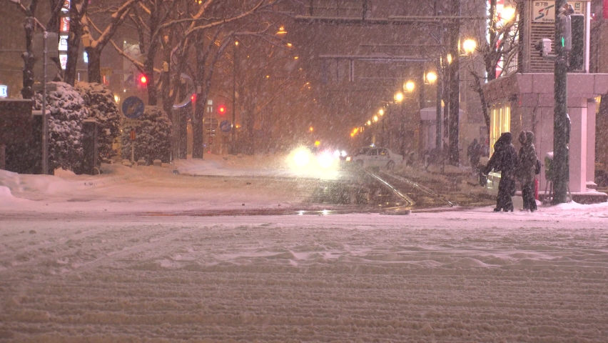 SAPPORO, HOKKAIDO, JAPAN - FEB 2020 : Snow scenery around Susukino city area at night. View of snow falling at downtown street. Japanese cold winter and snowing season concept video.