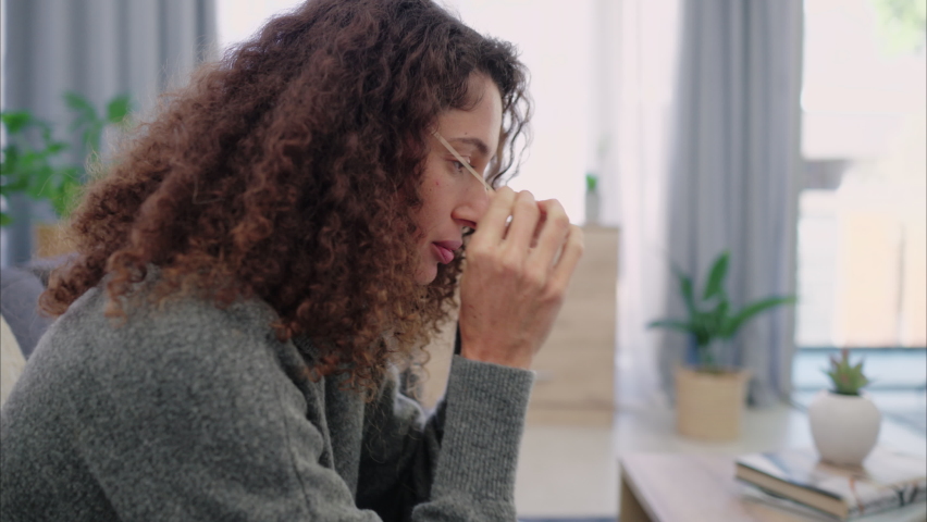 Doubt, thinking and mental health with a woman relax on the couch to rest and free her mind at home. Depressed latino female depression from anxiety, sad or fear on the couch in the living room | Shutterstock HD Video #1094996167