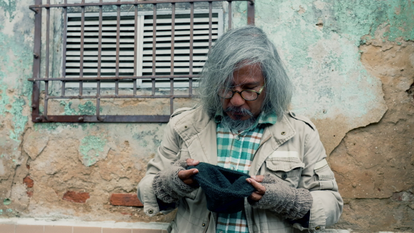 
Pity homeless aged man with eye glasses begging for food, money sitting on sidewalk street, unemployed miserable street man hungry raise hands for help, social problem homeless people on the street