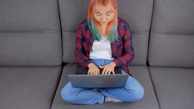 Young woman typing text on laptop keyboard. Freelancer person working on notebook computer on couch at home. Download stock video clip with freelance writer 