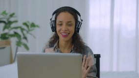 Black african american woman sitting in room wear earphones using laptop for remote work meeting team working from home. Smiling female manager talk look at camera in online video chat, distance job.