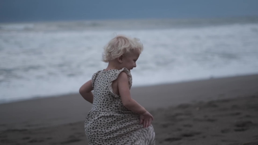 Slow motion footage of a little blond baby in a baby cloak running alone along the ocean shore. She rejoices in the feeling of freedom, that she can run wherever she wants. | Shutterstock HD Video #1095005137