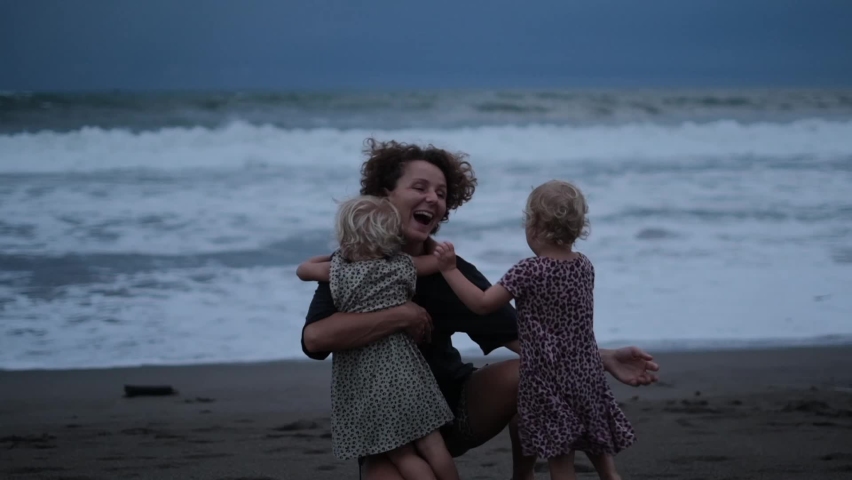 A young mother embraces her two daughters, who ran towards her after a short separation. The girls did not see their mother and missed the main person in their lives very much. | Shutterstock HD Video #1095005141