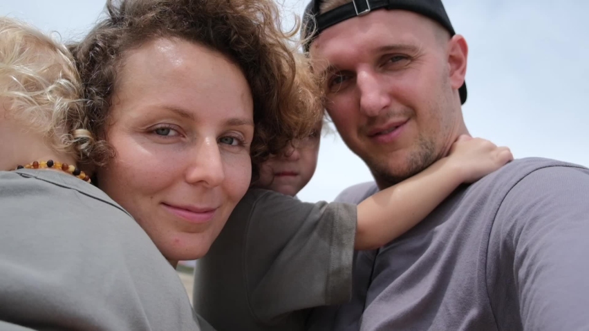 A married couple takes a close-up of themselves. They have a sudden video session with their family, who caught them walking with their children on the beach along the ocean. | Shutterstock HD Video #1095005149