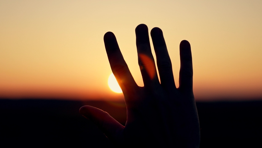 Light backdrop. Sunlight sky. Silhouette of palm of hand at sunset close-up. Man stretches his hand to sun silhouette. man's hand in sun close-up. concept of dreams, religion, motivation Royalty-Free Stock Footage #1095006719