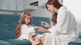 A young woman paints her little daughter's nails at home. - Powered by Shutterstock - Get 15% off with code: PIKWIZARD15