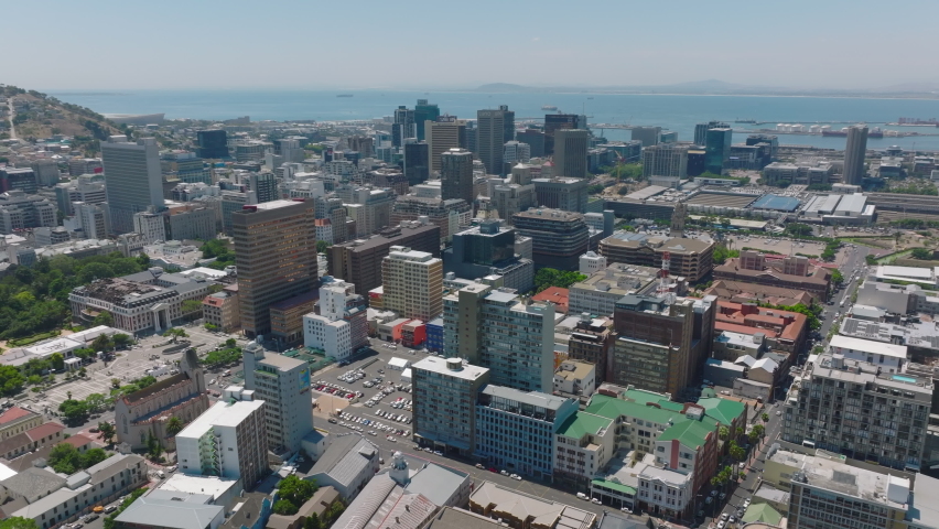 Slide and pan footage of multistorey commercial downtown buildings. Sea surface in distance. Cape Town, South Africa