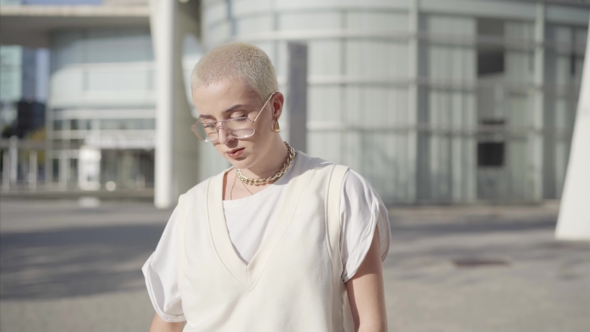 Portrait of woman with shaved hair looking at the camera serious. Confident young caucasian female standing outdoors. High quality photo