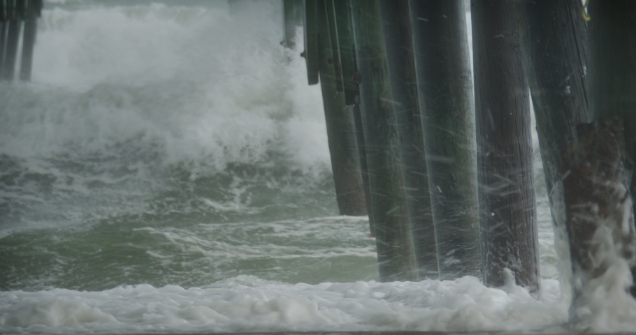 Sea foam and water are blasted around under an ocean pier as Hurricane Ian comes ashore. Royalty-Free Stock Footage #1095019129
