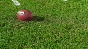 An American Football sitting in the grass as a red challenge flag comes next to the ball. 