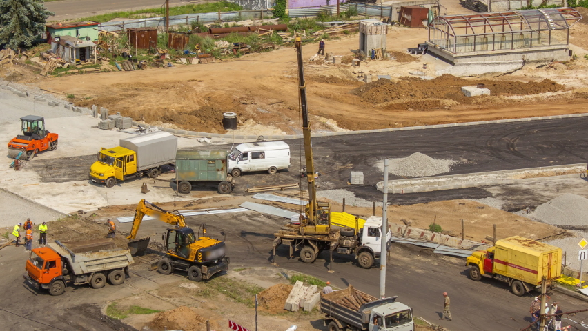Aerial view of large road construction site with several industrial machines timelapse. Earthmoving equipment with excavators and cranes moving concrete plates.