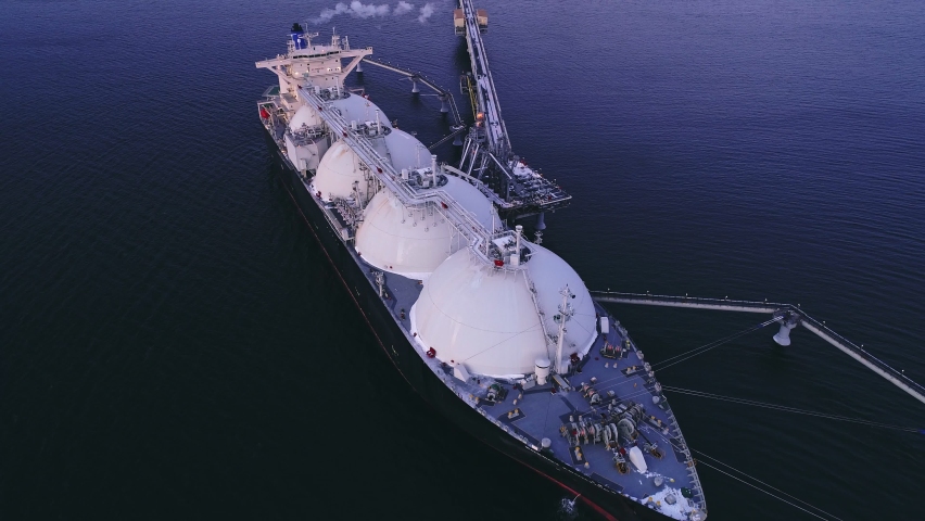 Aerial of Liquified Natural Gas LNG carrier moored to a small gas terminal. Fuel crisis. Sanctions Royalty-Free Stock Footage #1095030927