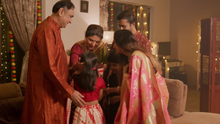 A happy smiling Hindu ethnic Indian family of Parents, grandchildren, and grandparents are greeting together while celebrating the occasion of Diwali in a decorated home. Festival relationship concept Royalty-Free Stock Footage #1095035413