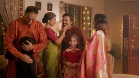 A happy smiling Hindu ethnic Indian family of Parents, grandchildren, and grandparents are greeting together while celebrating the occasion of Diwali in a decorated home. Festival relationship concept - Powered by Shutterstock - Get 15% off with code: PIKWIZARD15
