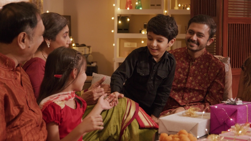 A happy smiling Hindu ethnic Indian family of Parents, grandchildren, and grandparents are greeting together while celebrating the occasion of Diwali in a decorated home. Festival relationship concept Royalty-Free Stock Footage #1095035467