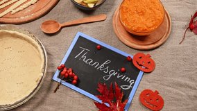 Top view. Steadicam shot: Fresh raw ingredients for making an American traditional pumpkin classic pie with a crispy crust. Thanksgiving written with chalk on board. Copy advertising space. Still life - Powered by Shutterstock - Get 15% off with code: PIKWIZARD15