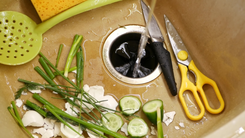 Organic garbage in sink with built-in food waste disposer. vegetable or fruits peels, remains and leftovers and disposal grinder. Zero waste, sustainable development and garbage separation concept. | Shutterstock HD Video #1095037611